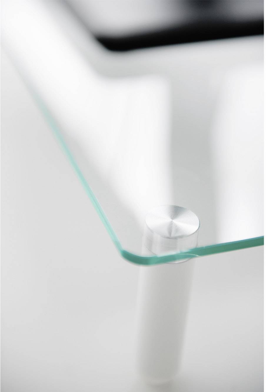 Een glazen tafel met afgeronde hoek, gefotografeerd op een witte ondergrond. Minimalistisch design, moderne sfeer.