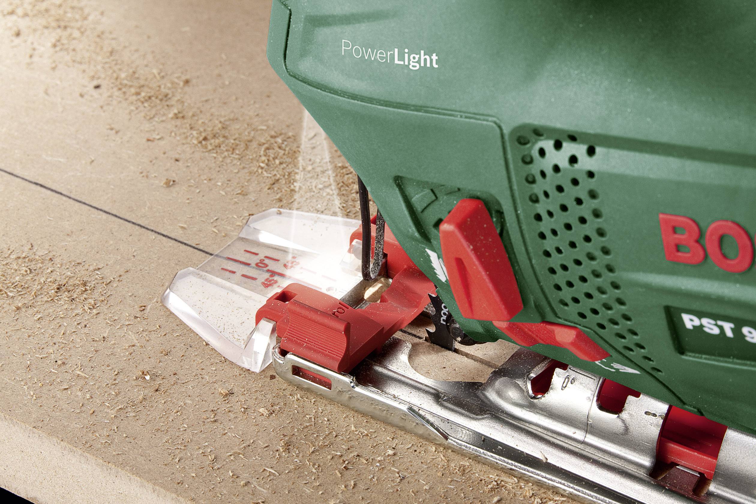 Een groene Bosch decoupeerzaag snijdt precies over een houten oppervlak. Een ingebouwde lamp verlicht de zaagzone.