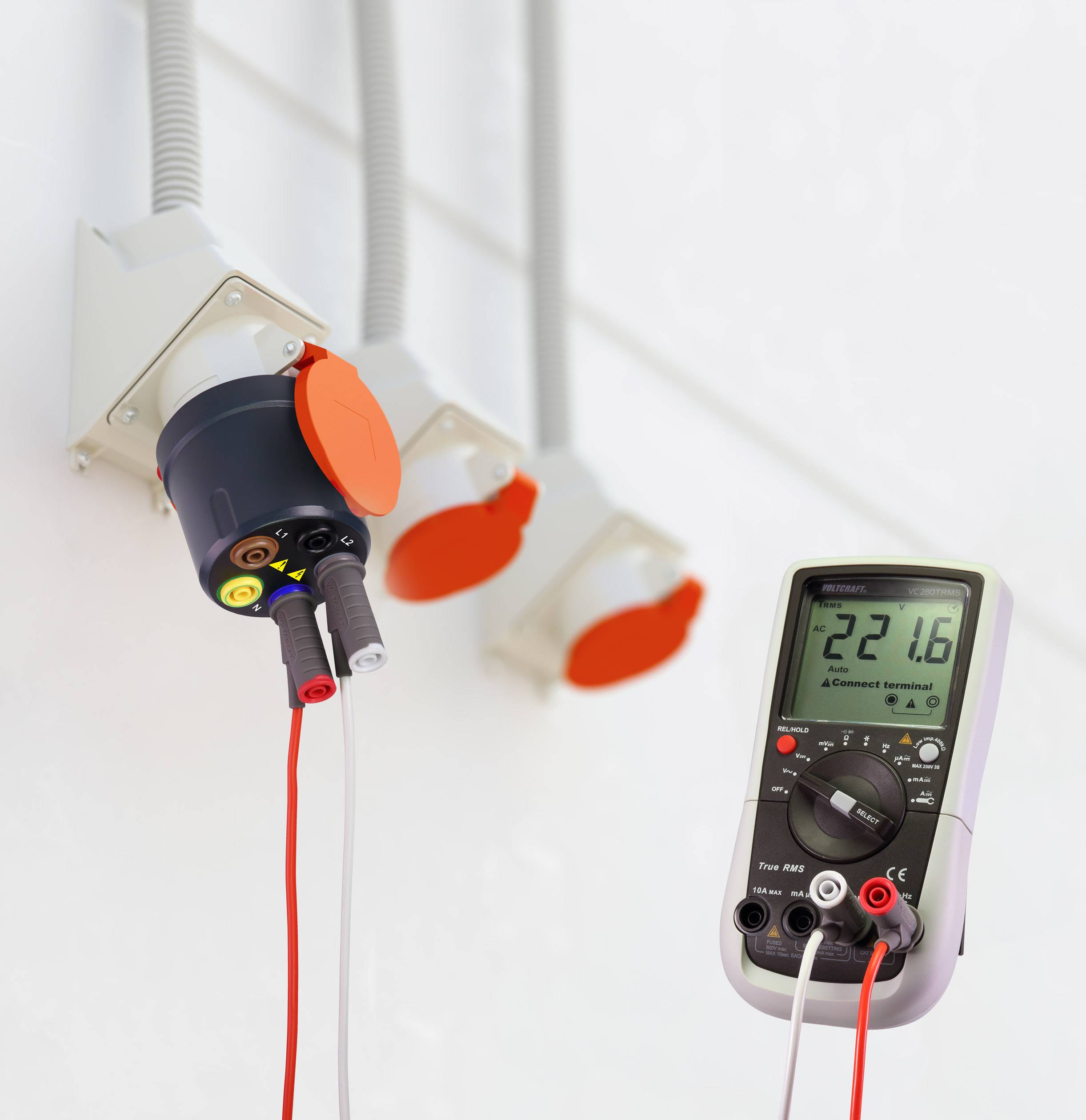 Een multimeter meet een spanning van 22,16 V bij een stopcontact met meerdere aansluitingen. De weergave is digitaal.