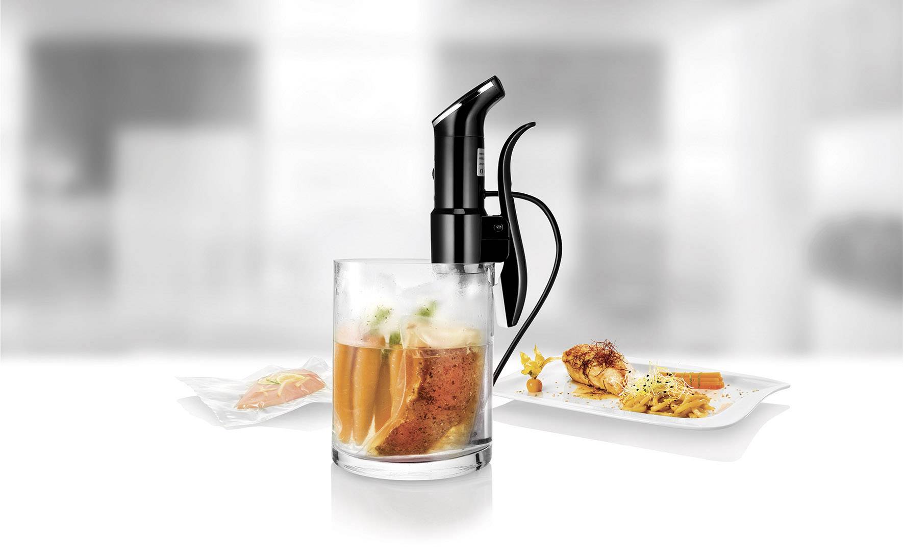 Sous-vide-apparaat naast een pot met vacuüm verpakte voedingsmiddelen. Op de achtergrond zijn borden met verschillende gerechten te zien.
