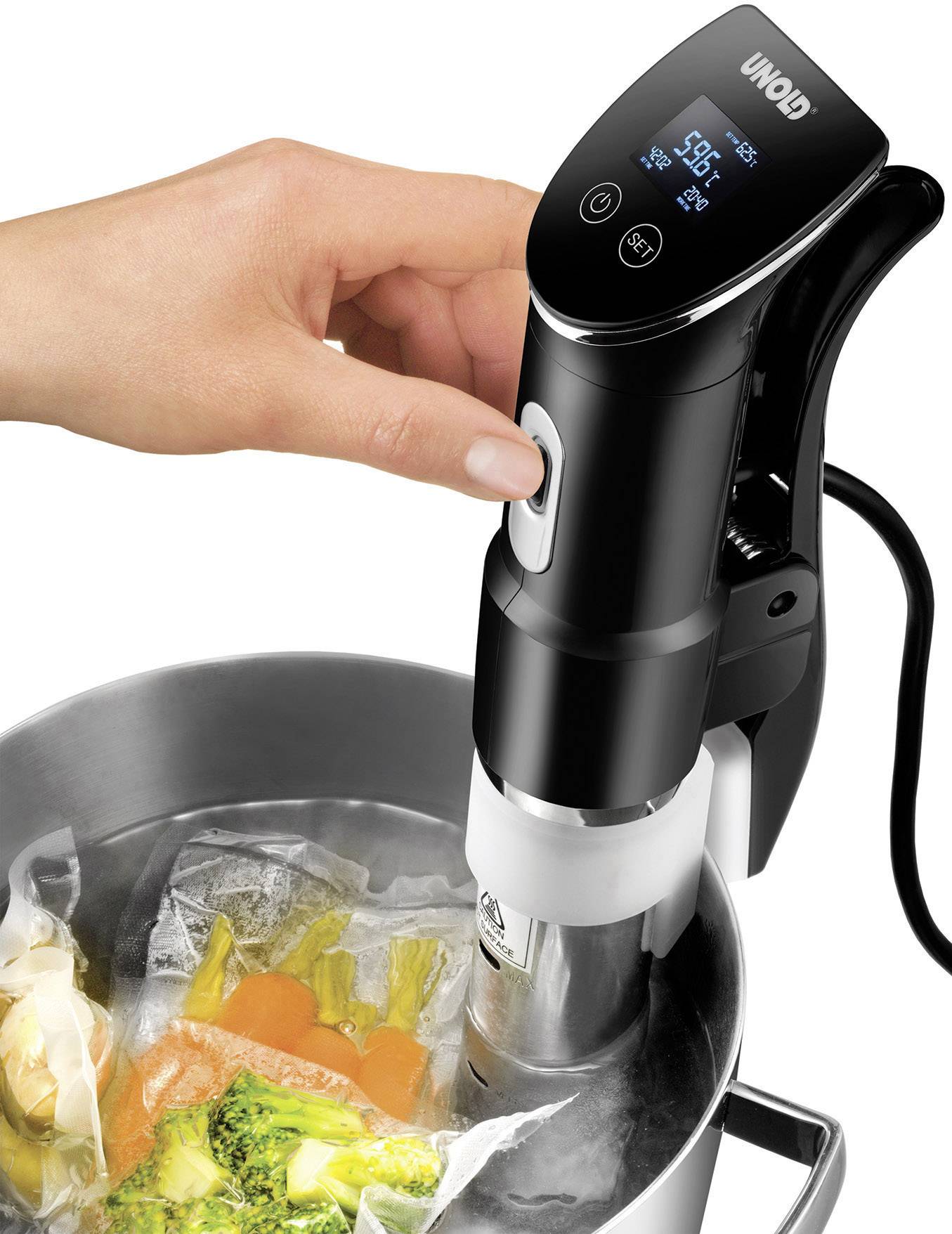 Een hand bedient een sous-vide-apparaat dat water verwarmt tot 58,6°C in een pan met vacuüm verpakte groenten.