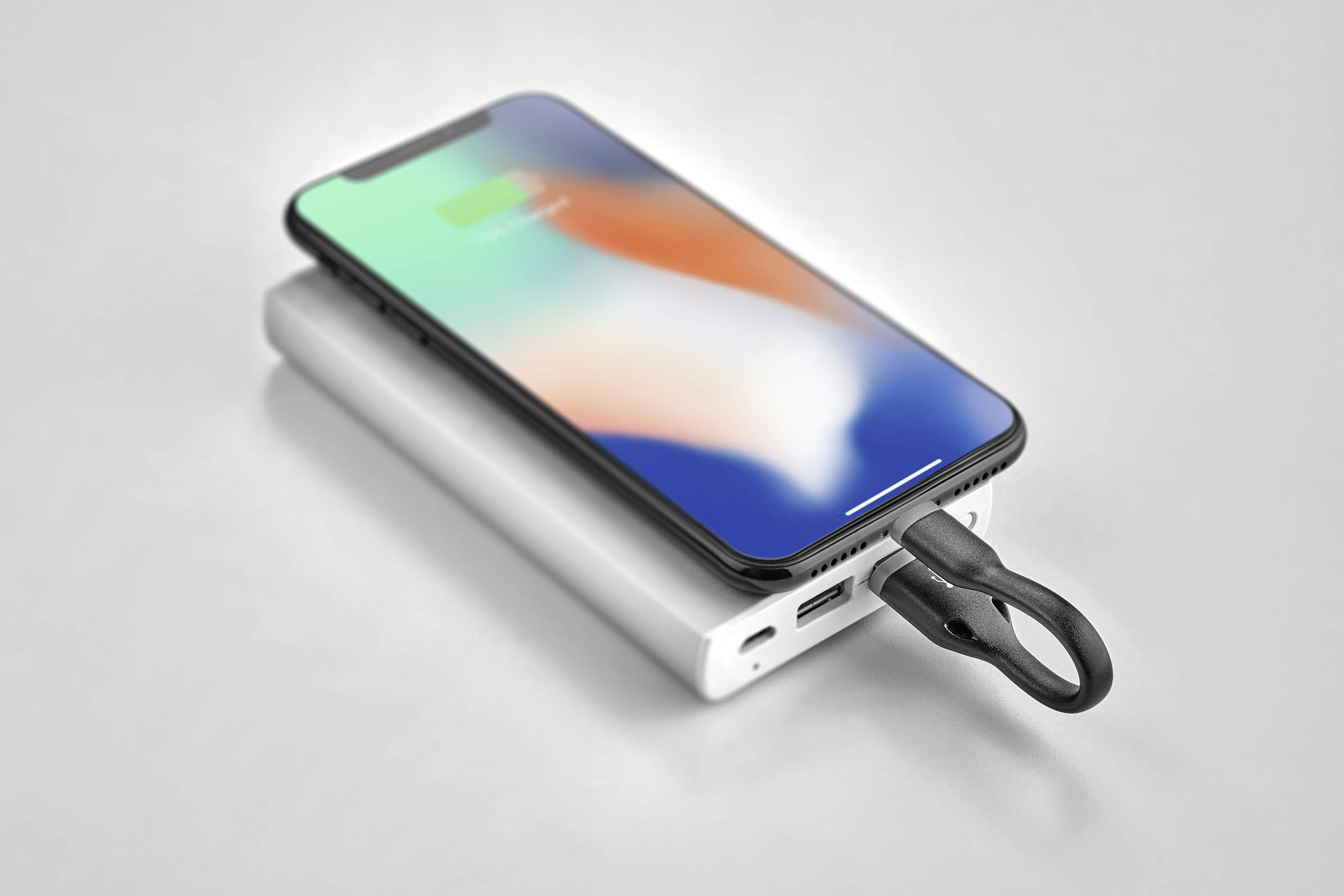 Een smartphone wordt opgeladen met een draagbare powerbank. Het display toont een groene laadmeter.