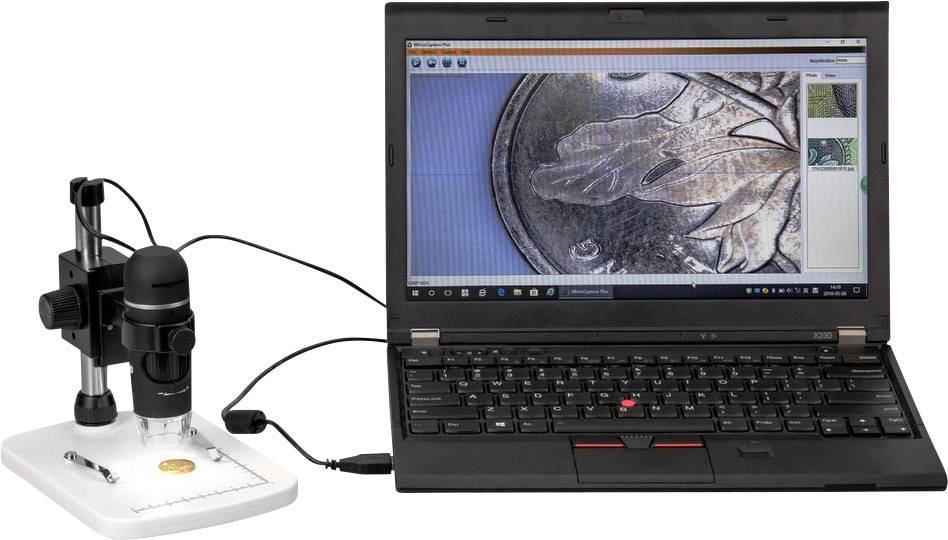 Een laptop toont een close-up van een munt op het scherm. Een digitaal microscoop is verbonden met de laptop en onderzoekt de munt.