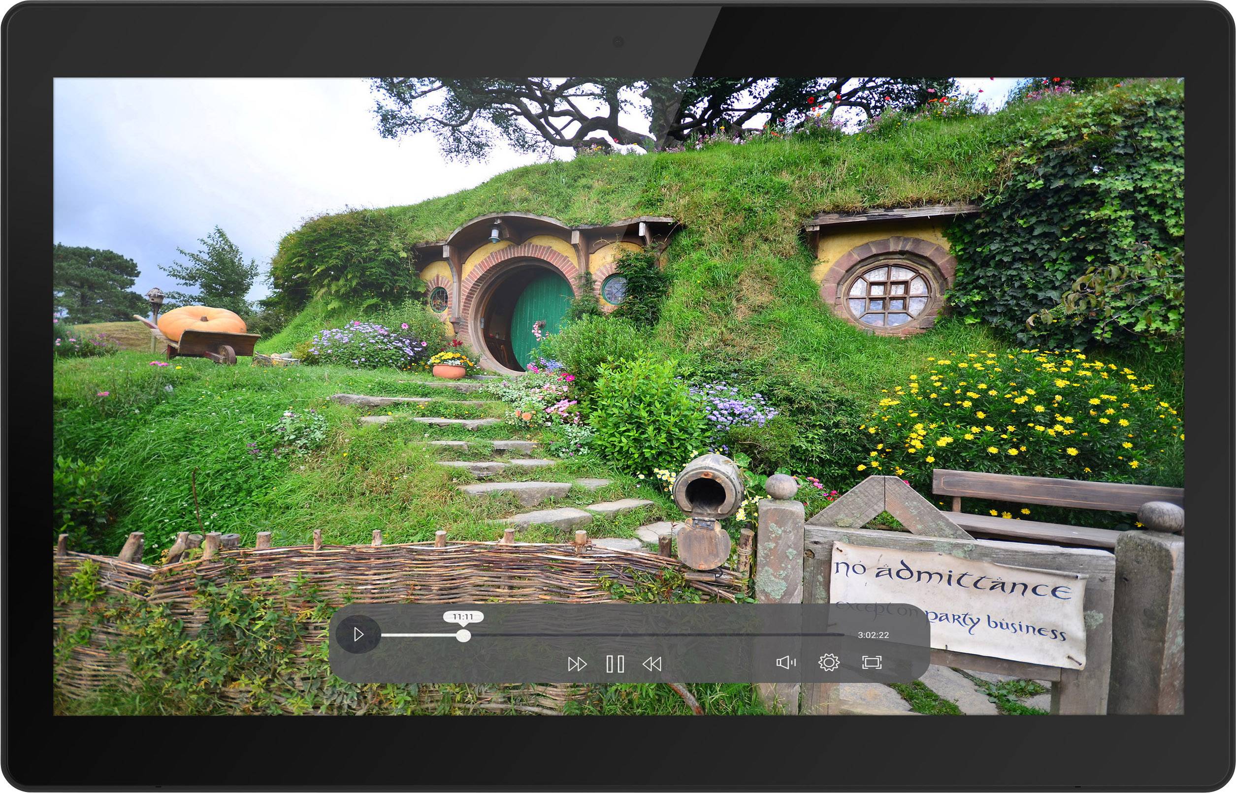 Een Hobbit-huis met een ronde deur en een keurig onderhouden tuin. Een bordje zegt 'geen toegang, tenzij voor feestzaken'.