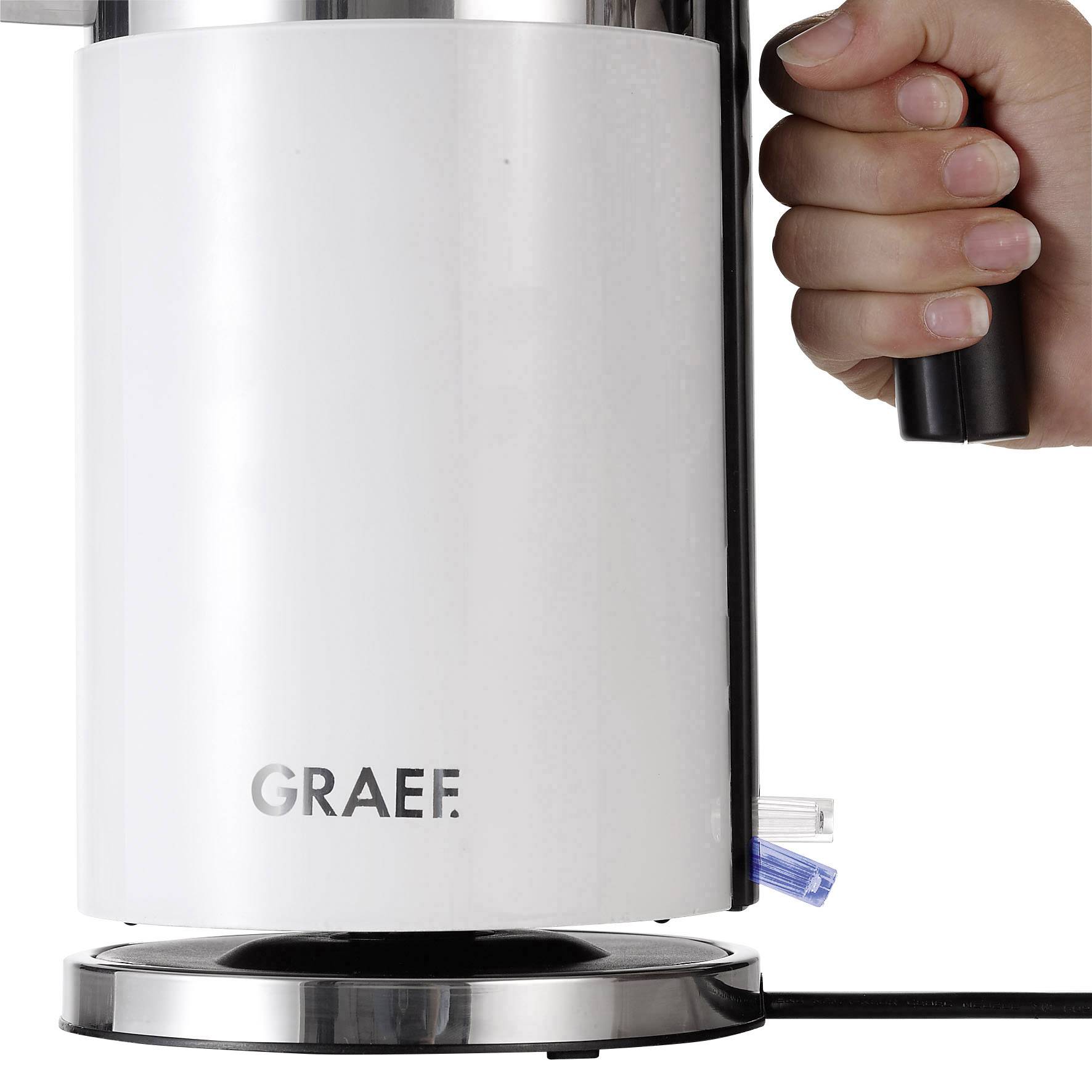 Een hand houdt de handgreep vast van een elektrische waterkoker op een standaard. De waterkoker is van metaal met het merk 'Graef'.
