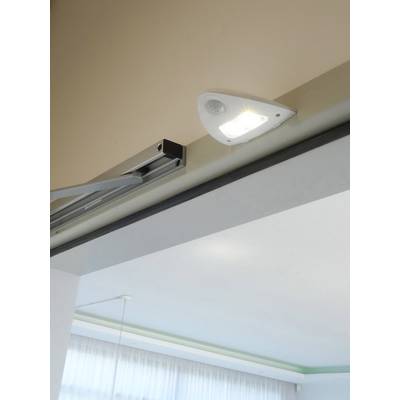 Een moderne lamp aan het plafond schijnt helder over een ruimte met grote ramen die natuurlijk licht binnenlaten.