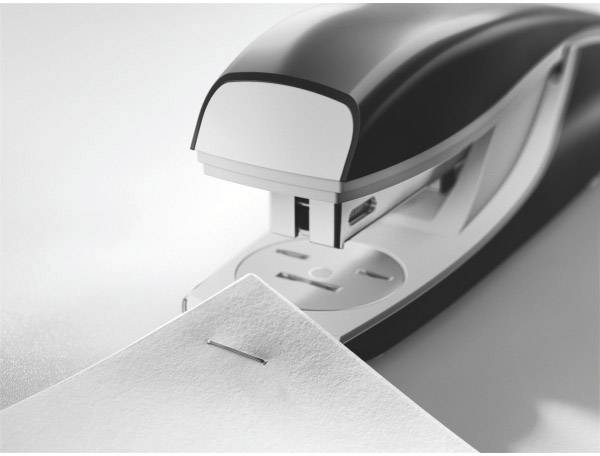 Een zilveren en zwarte nietmachine hecht een vel papier. De close-up toont de nietmachine in een kantooromgeving.