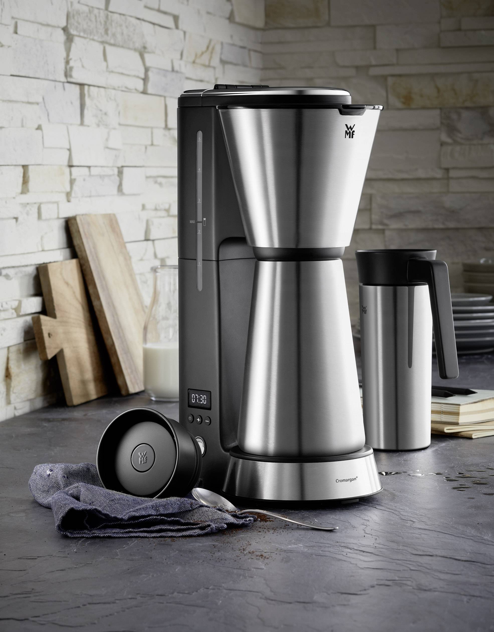 RVS koffiemachine staat op het aanrecht naast een koffiekop en melk. Moderne en elegante keukenomgeving.