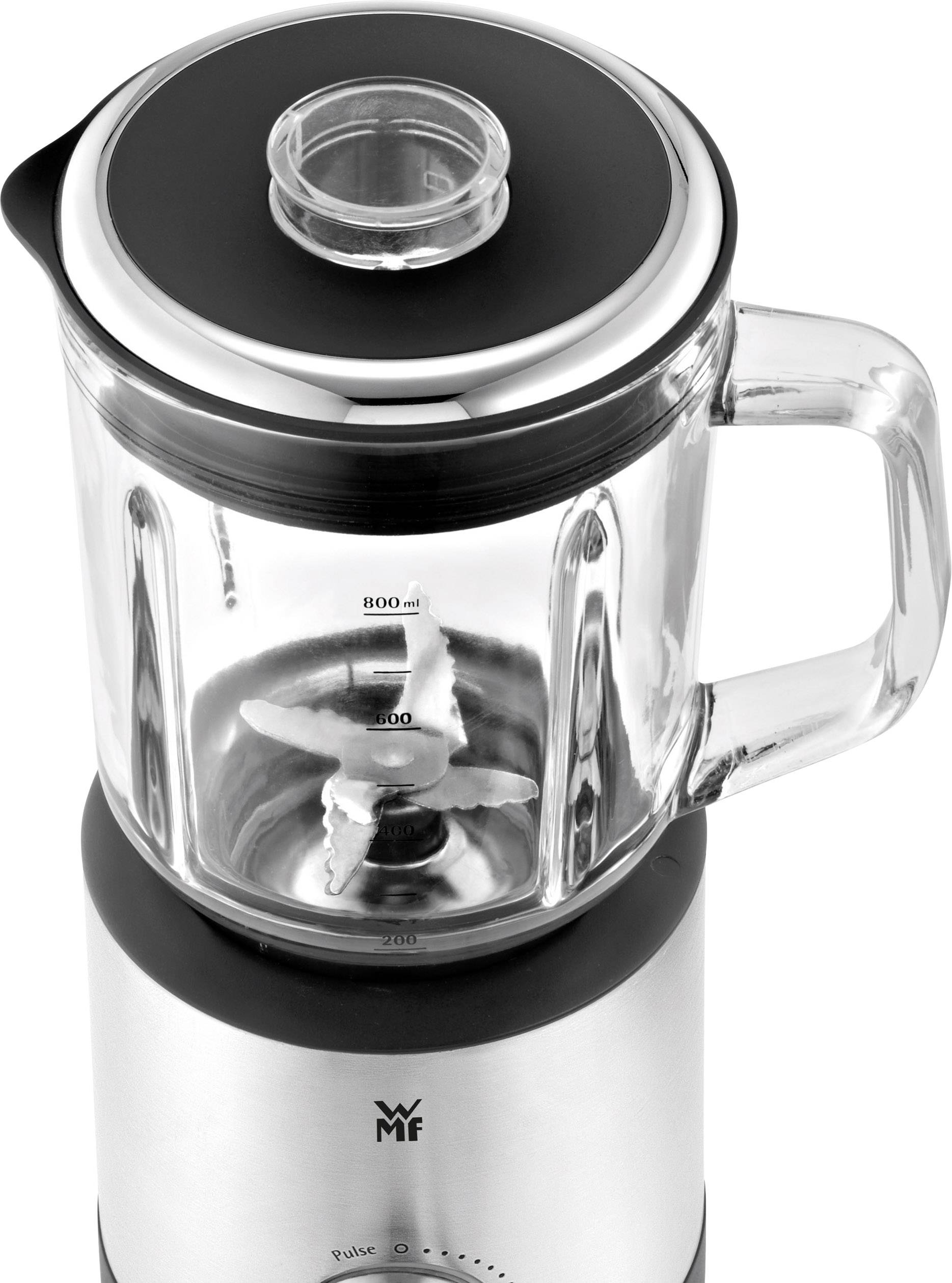 Een glazen blender met zilveren voet, transparante mengbeker en zichtbare roestvrijstalen messen. Inhoudsschaal gemarkeerd tot 800 ml.