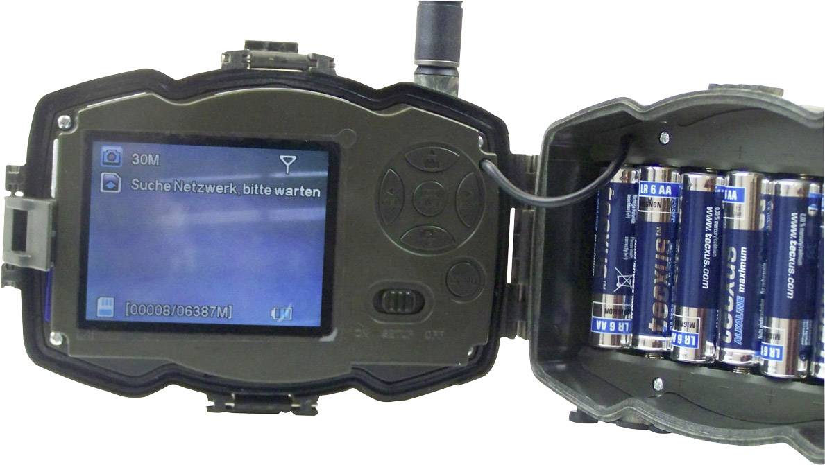 Een wildcamera toont op het display de melding 'Zoekt netwerk, even geduld'. Rechts zijn verschillende batterijen zichtbaar.