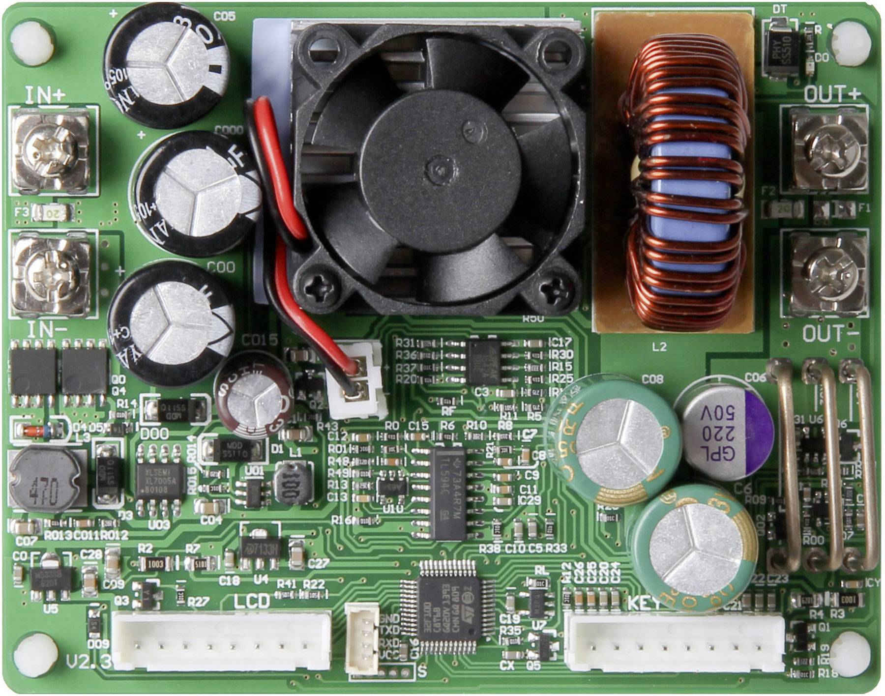 Een groene printplaat met meerdere condensatoren, spoelen, aansluitingen en een kleine ventilator, die elektronische componenten voorstelt.