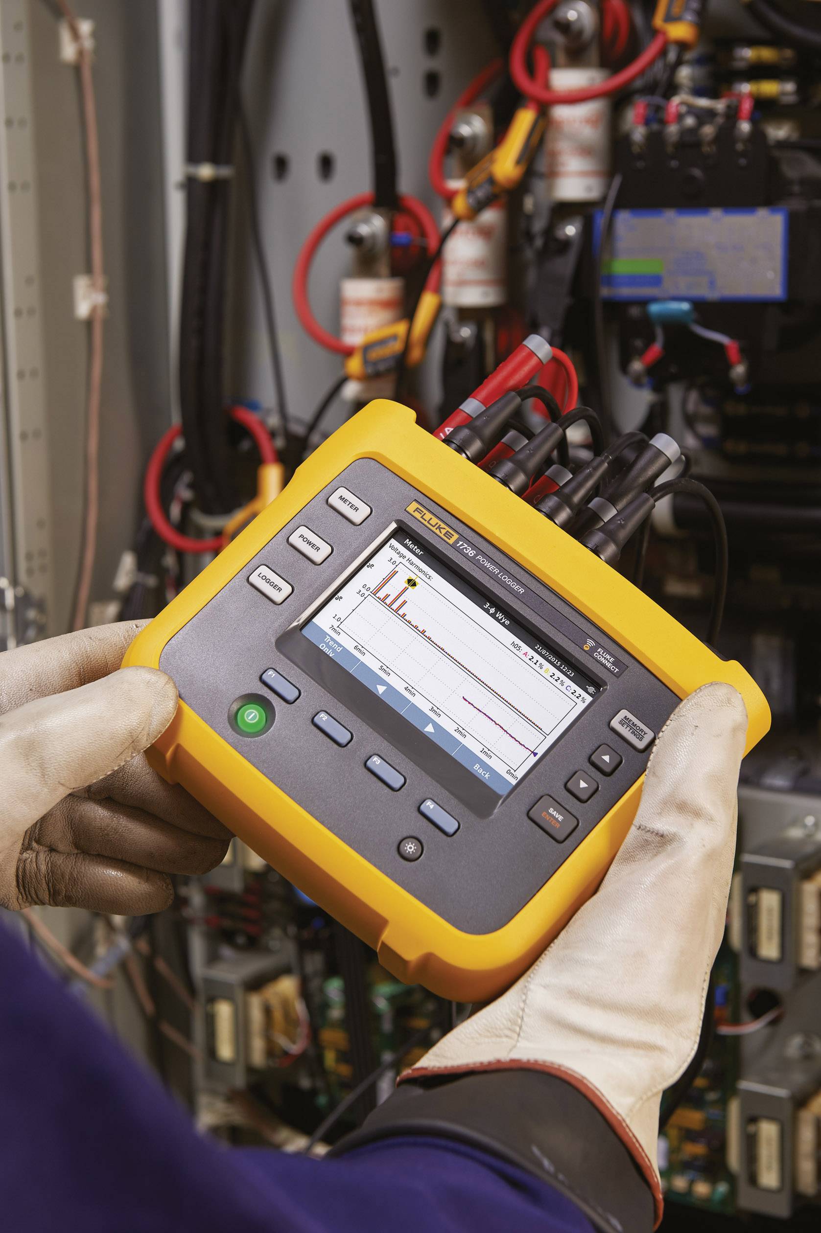 Handen van een persoon in beschermende handschoenen houden een draagbaar elektronisch meetapparaat vast voor het analyseren van elektrische verbindingen.
