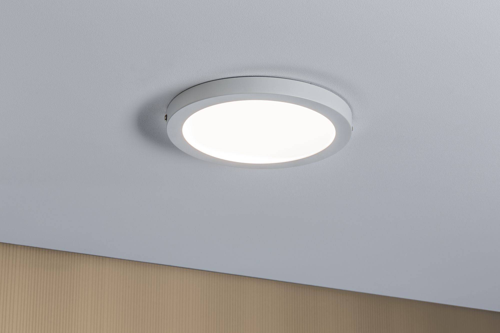 Ronde plafondlamp met witte rand aan een beige-grijze plafond, schijnt helder.