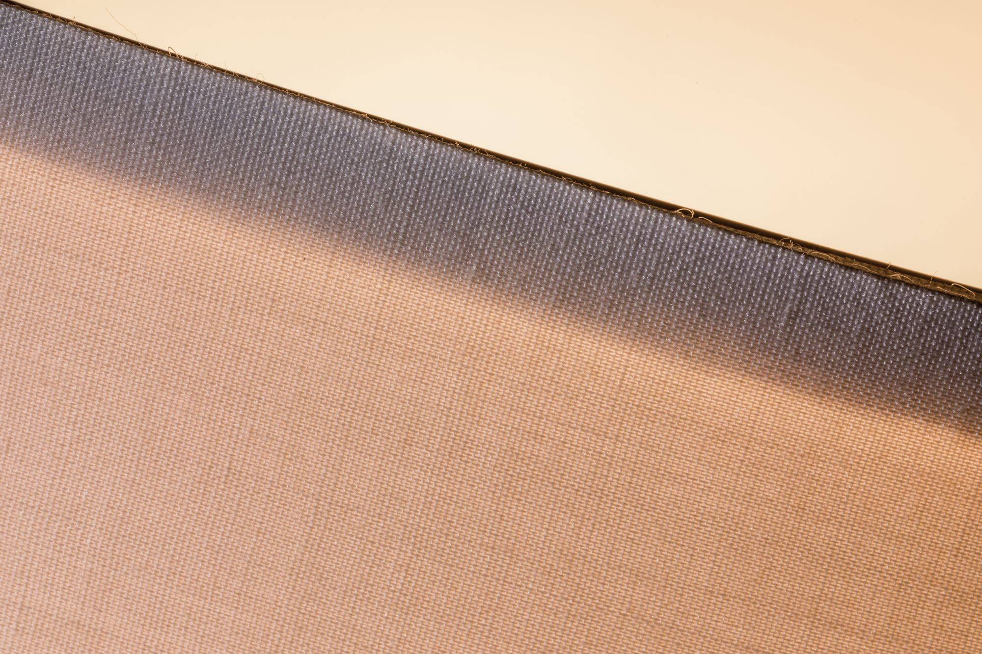 Close-up van een gestructureerd, hellend oppervlak met een kleurverloop van donker bovenaan naar licht onderaan.