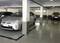 Een ondergrondse parkeergarage met twee geparkeerde auto's, waarvan één een zilveren voertuig in het midden.
