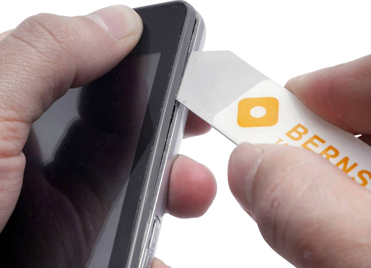 Een persoon gebruikt een speciaal gereedschap om het display van een smartphone voorzichtig te openen.