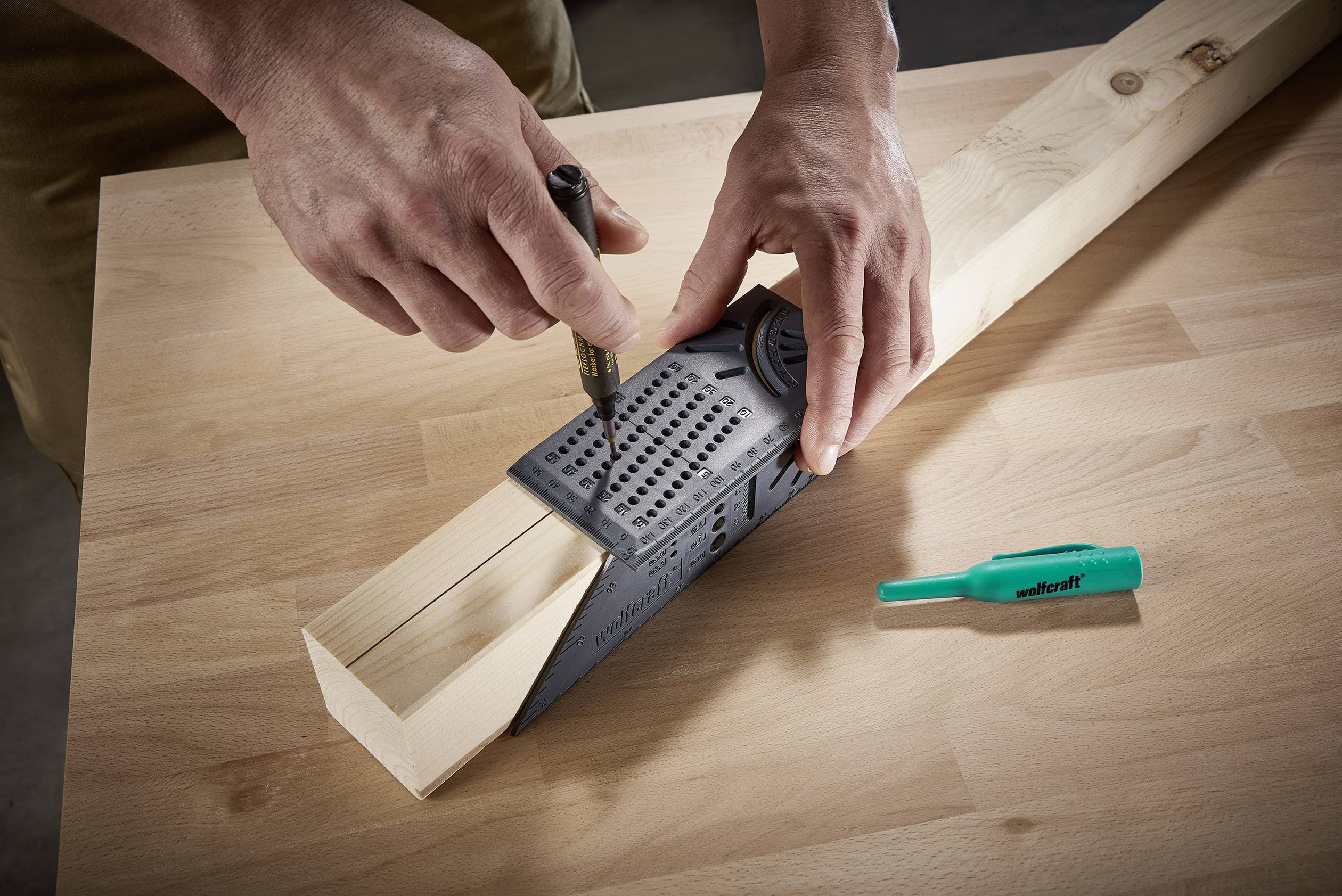 Een persoon gebruikt een multifunctioneel meetinstrument om nauwkeurige markeringen aan te brengen op een stuk hout op een werktafel.