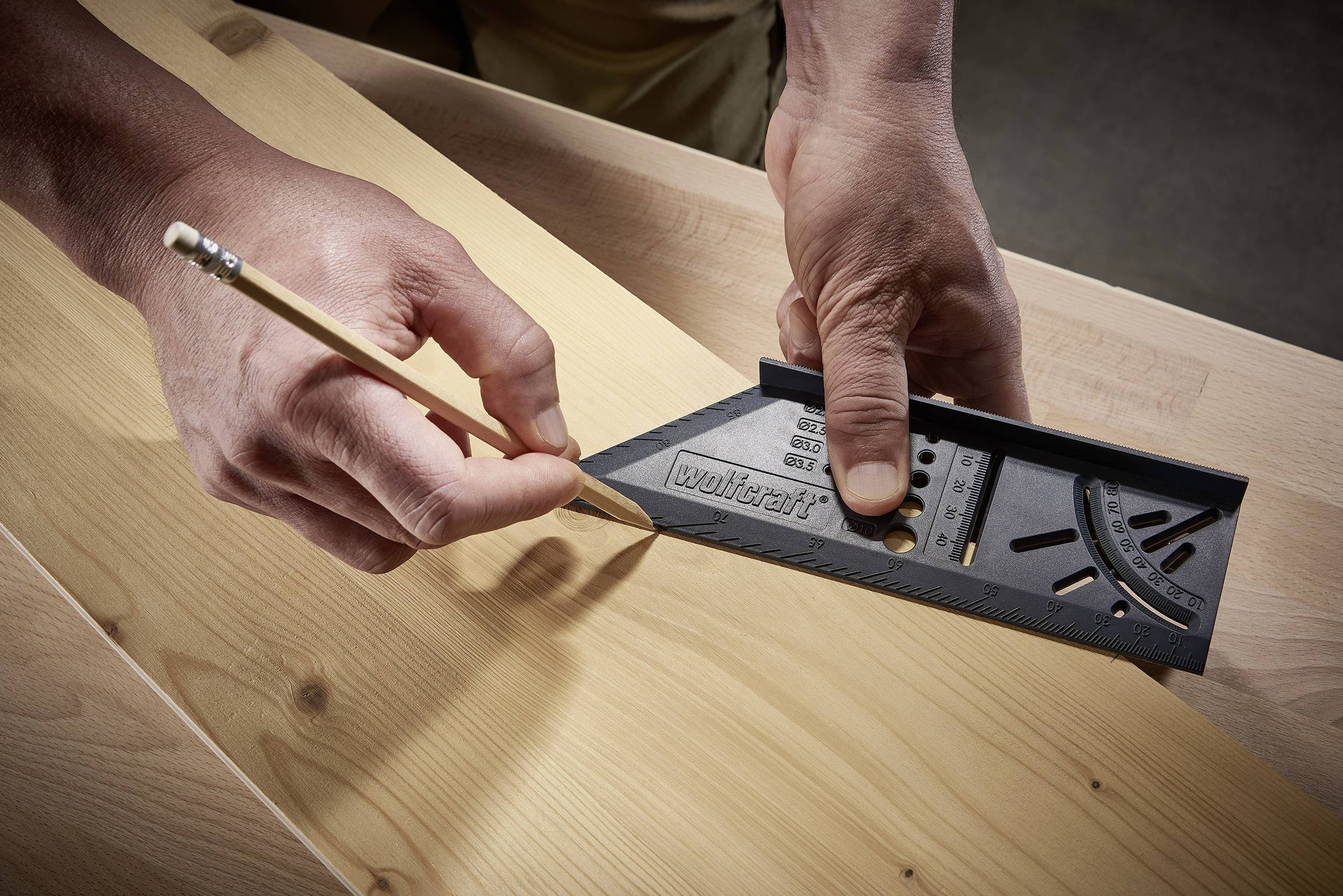Een persoon trekt met een potlood een lijn op een houten plank terwijl hij een hoekmetingsgereedschap gebruikt voor nauwkeurige uitlijning.
