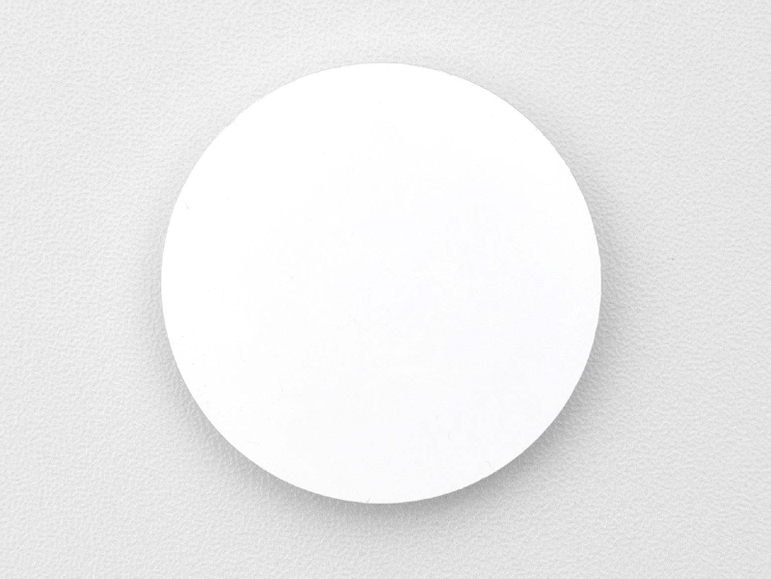 Een witte, ronde schijf ligt op een lichtgrijze oppervlakte.