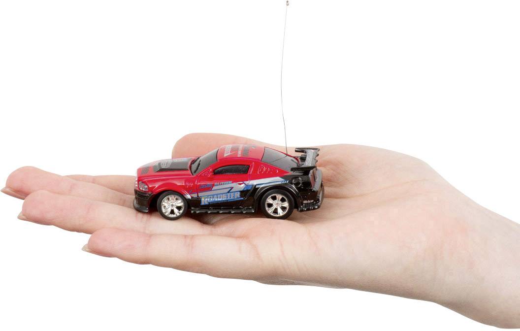 Een open hand houdt een kleine rode speelgoedauto met antenne vast, die eruitziet als een bestuurbare auto.