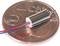 Een minuscule elektromotor ligt op een 5-eurocent-munt om de kleine afmeting van de motor in vergelijking met de munt te illustreren.
