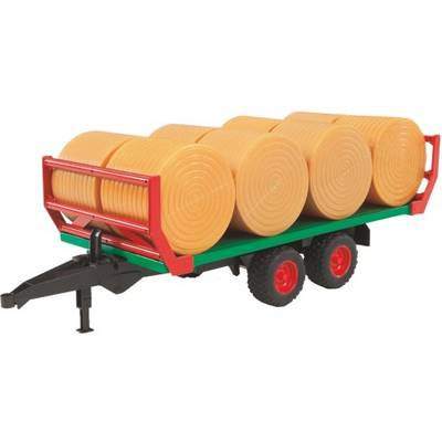 Speelgoedaanhanger met zes gele ronde ballen, op een groene en rode aanhanger, getrokken door twee zwarte wielen.