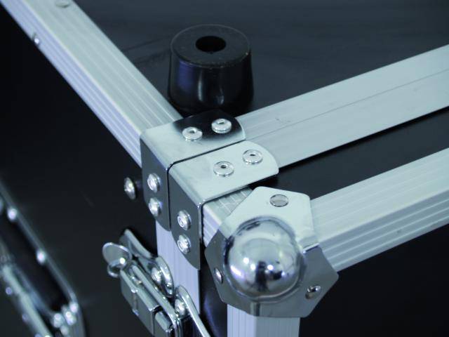 Hoek van een zwarte transportkoffer met zilveren metalen verstevigingen en sluitingen.