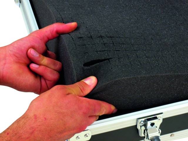 Handen passen schuimstof aan in een koffer om het aan een vorm te laten voldoen.