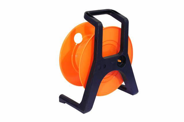 Een lege, oranje kabelspoel met een zwart kunststof frame, staand op een wit oppervlak.