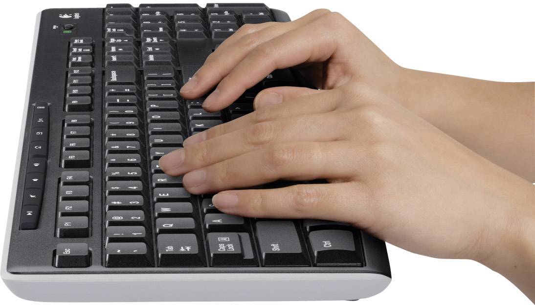 Twee handen typen op een zwart computertoetsenbord.