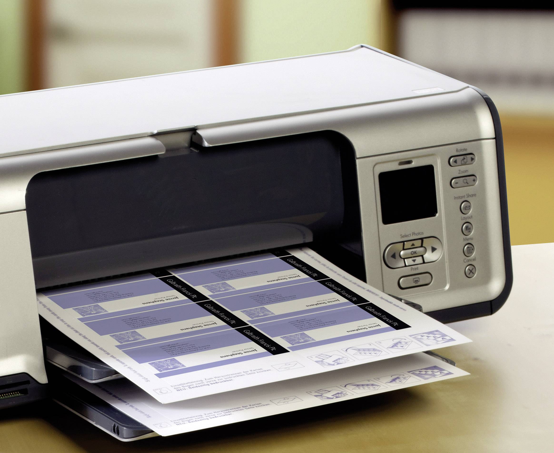 Een tafel-bureauprinter drukt etiketten af. De etikettenbladen verschijnen half bedrukt. De ruimte heeft een lichte en nette atmosfeer.