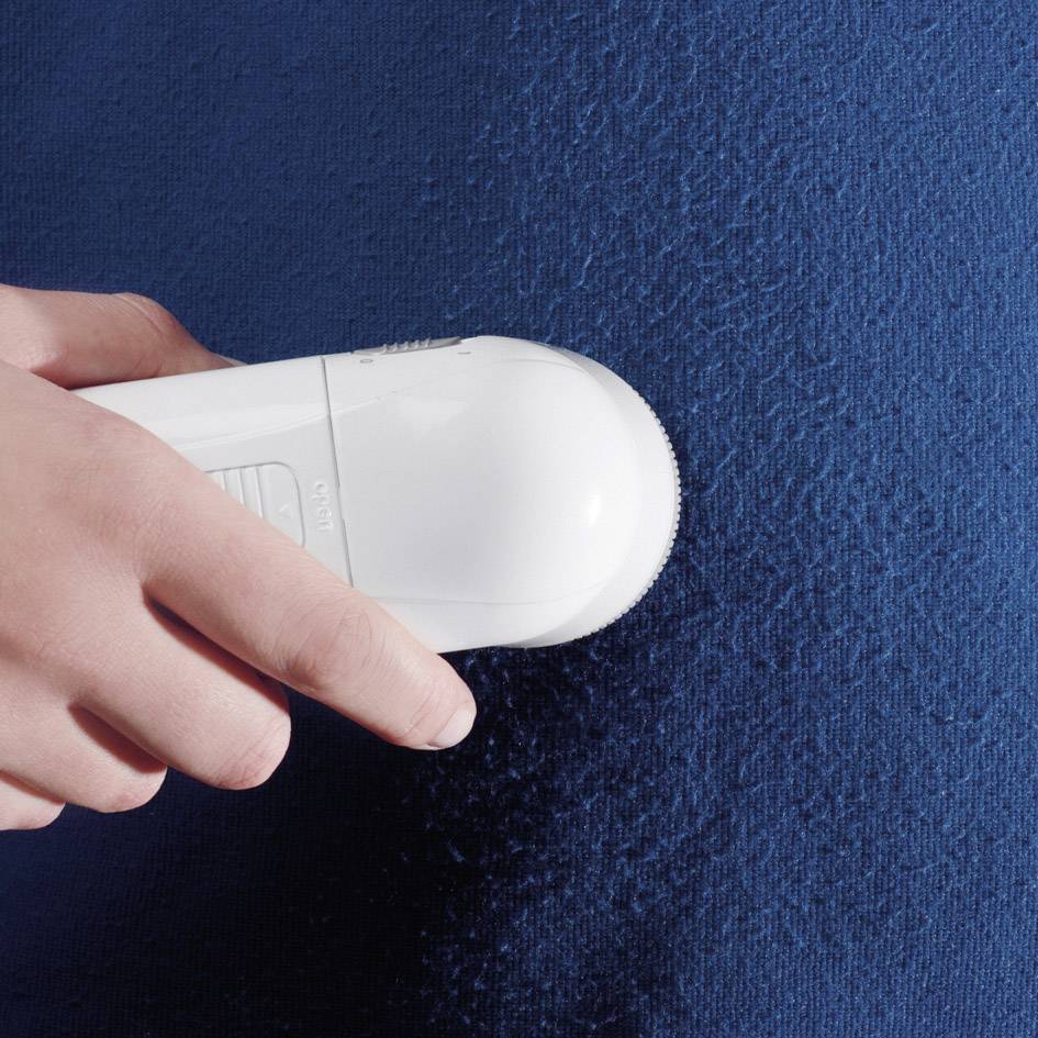 Een persoon houdt een wit deodorantspray en spuit het op een blauw shirt.