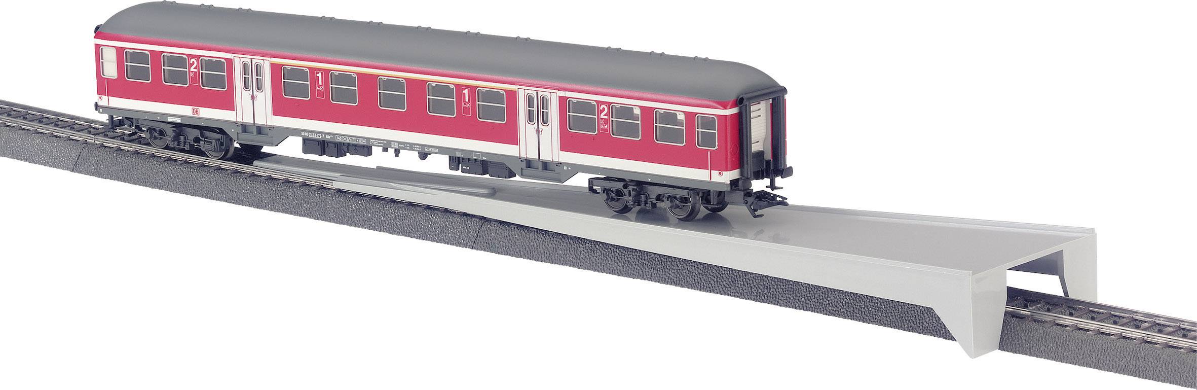 Een rode modeltreinwagon rijdt over een schuine brug op een spoor.