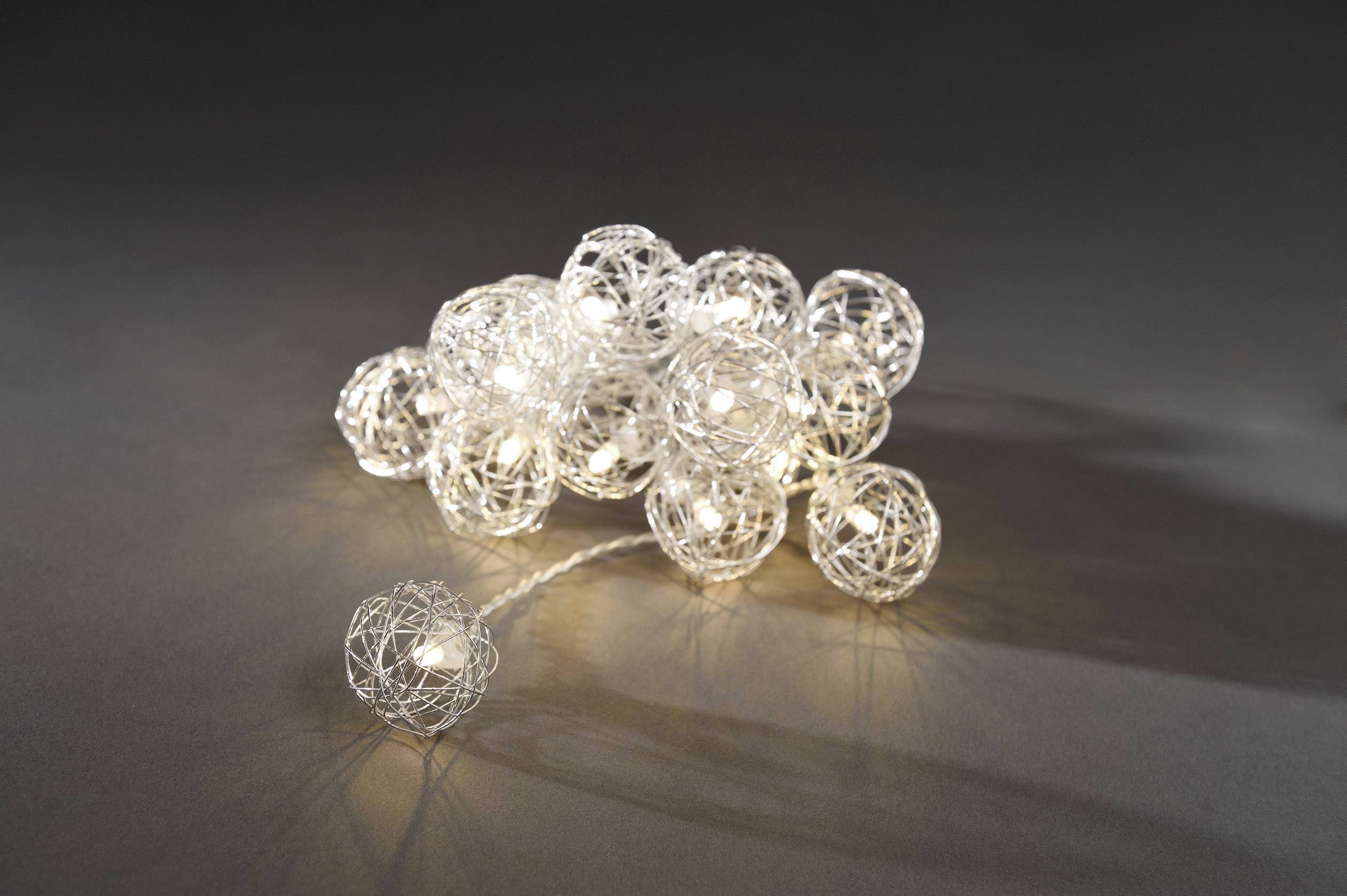 Een bundel decoratieve lichtkogels van zilverkleurige draad, die oplichten, ligt op een grijze oppervlakte.