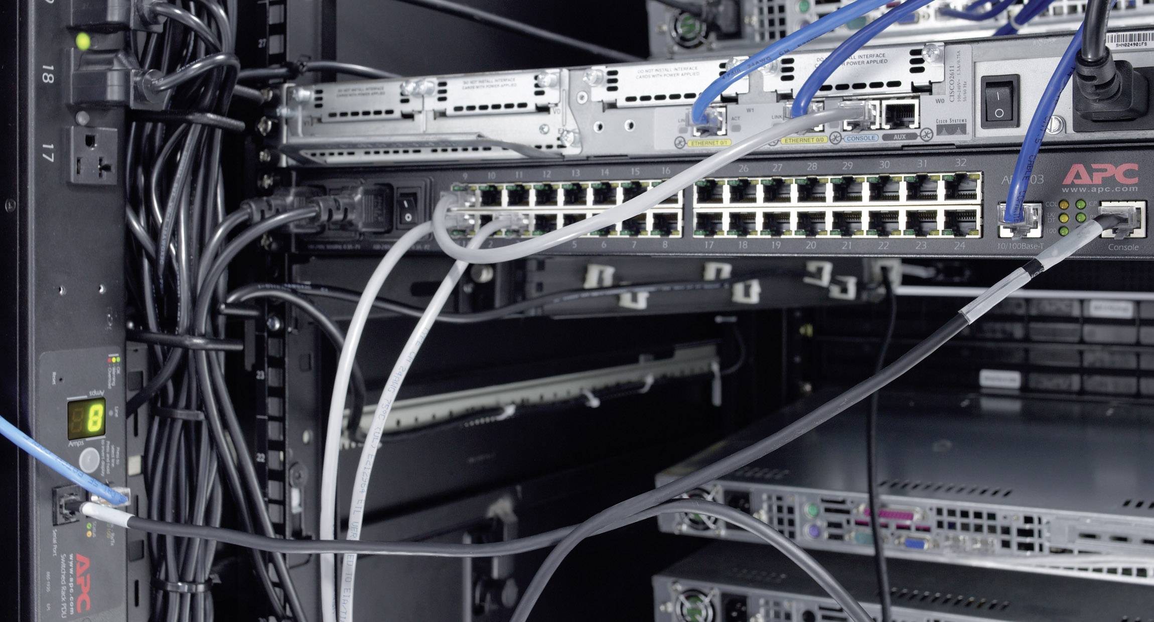 Een serverrek met kabels en netwerkapparatuur. Enkele kabels zijn aangesloten op een switch die deel uitmaakt van een netwerksysteem.