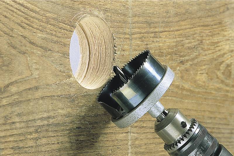 Boorkroon boort door houten plaat en laat een rond gat achter.