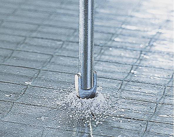 Close-up van een boor die in een betegelde vloer boort, genereert stof en toont het concrete doordringingsvermogen.