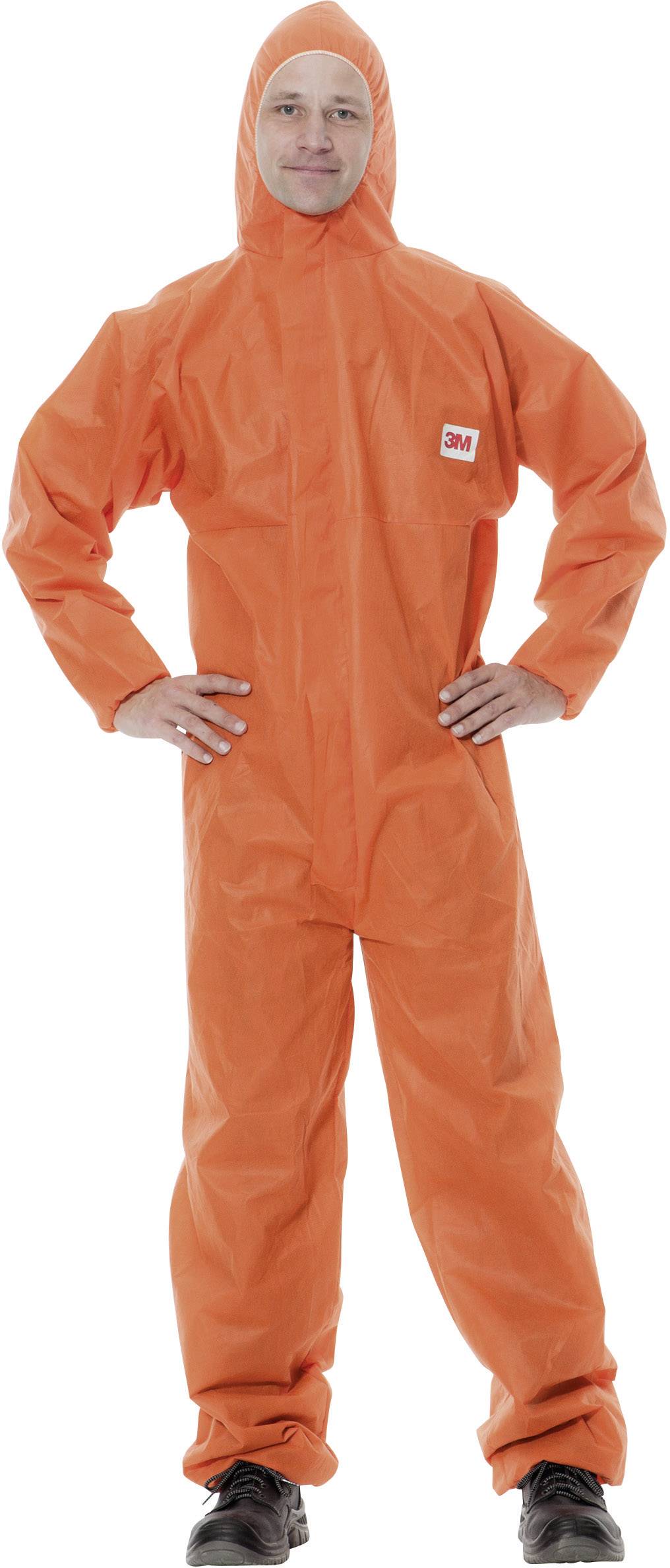Persoon in een oranje beschermingspak met capuchon, staat met de handen in de zij, voor een neutrale achtergrond.