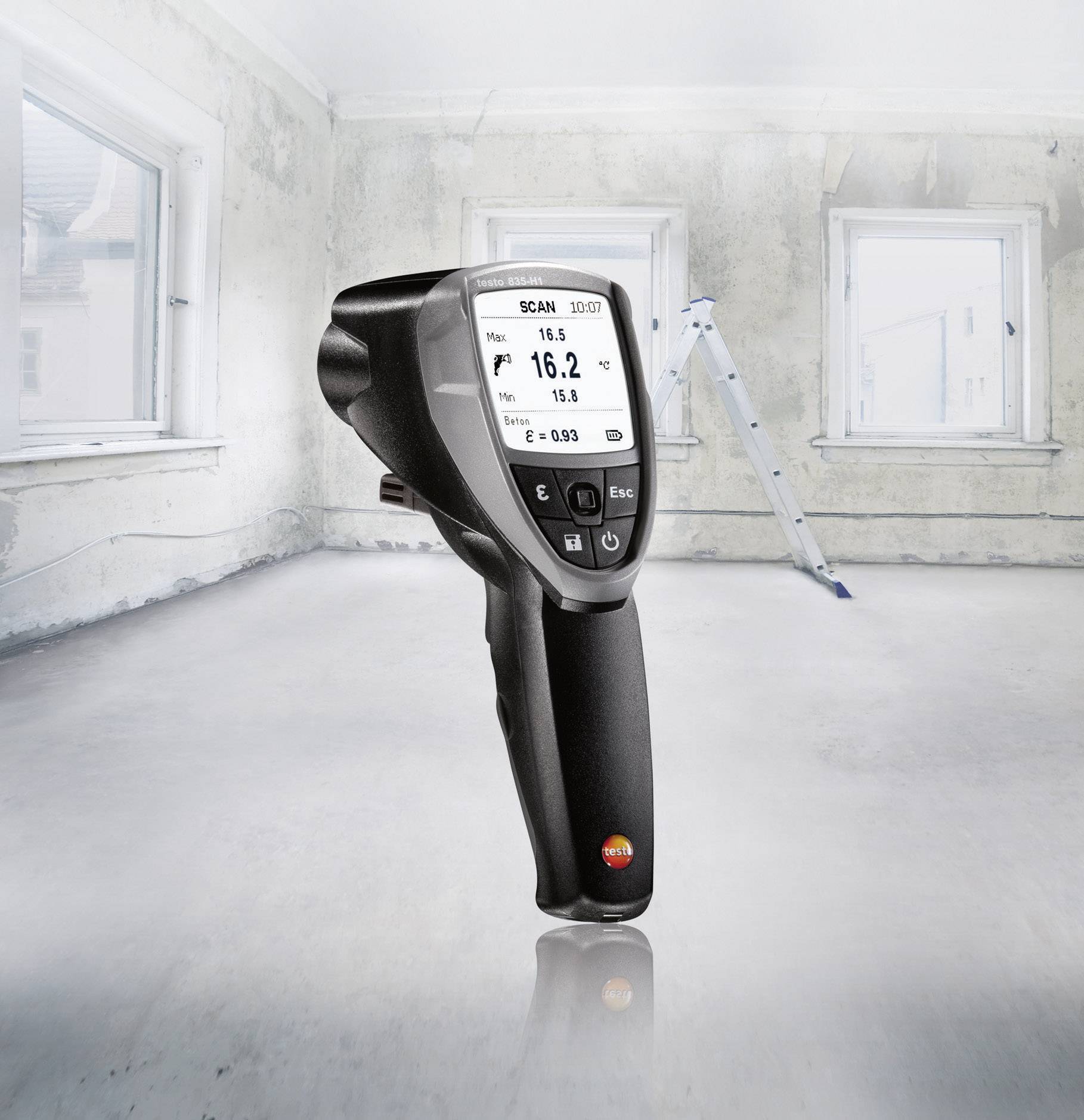 Een infrarood-thermometer toont 16,2 °C in een ruimte die aan renovatie toe is. Op de achtergrond zijn ramen en een ladder zichtbaar.
