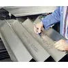 Een persoon in een blauwe werkjas schrijft wiskundige formules met een rode pen op metalen platen.