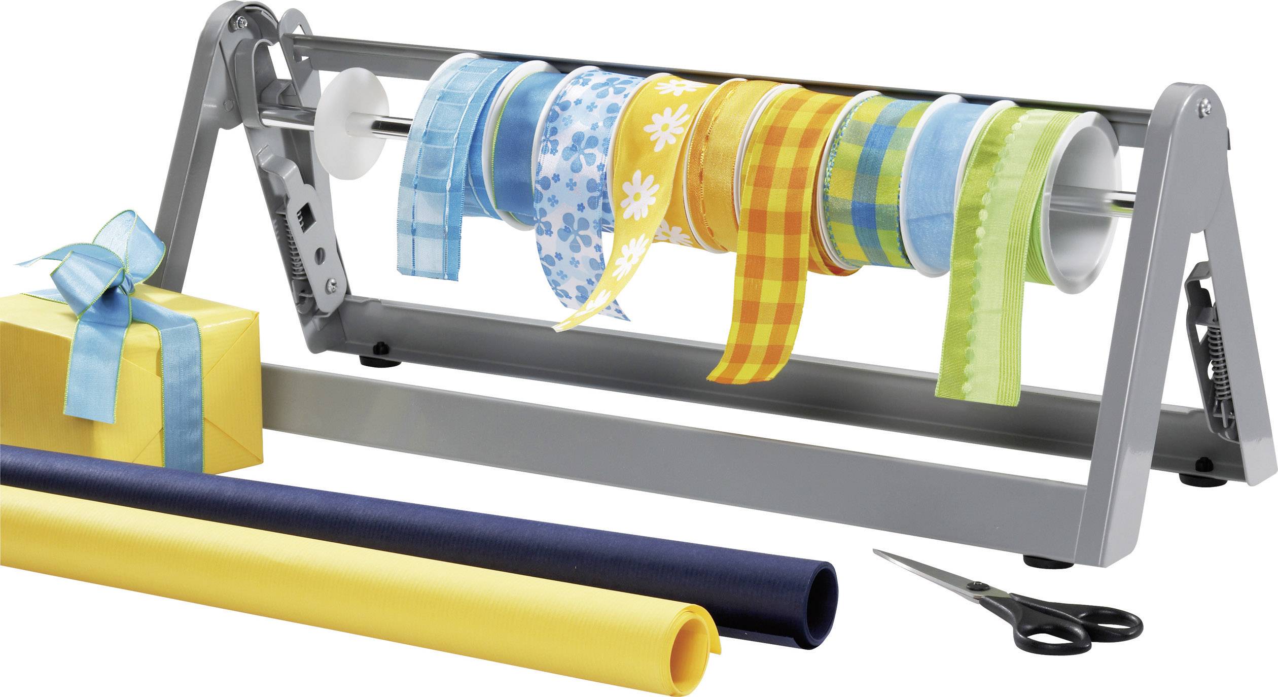 Een lintenhouder met verschillende gekleurde linten, een ingepakt cadeau met strik, twee rollen cadeaupapier en een schaar.