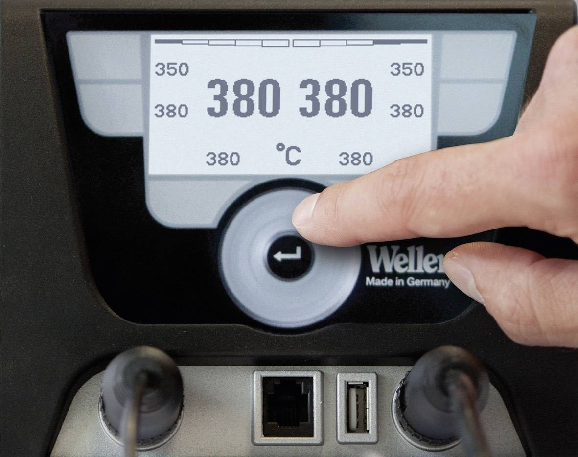Een vinger bedient de temperatuurinstelling van een elektronische soldeerstation. Op het display staat '380 °C'.