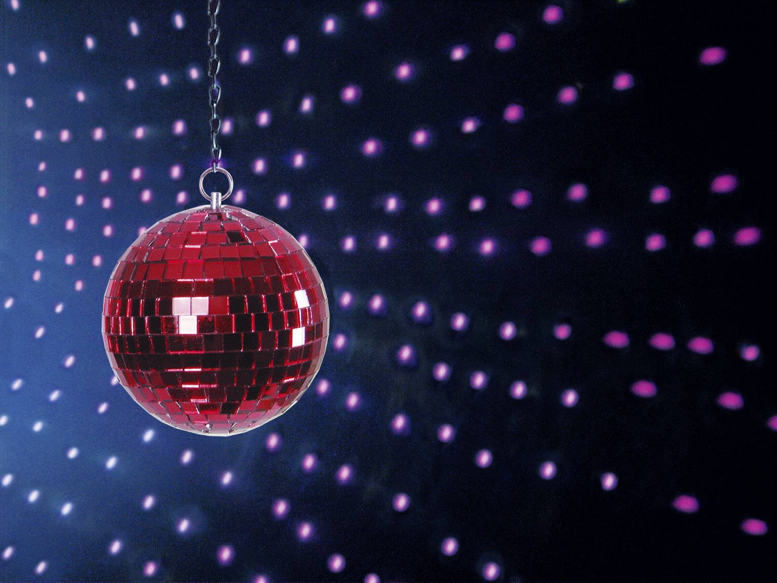 Rode discobal voor een blauwe achtergrond, die kleurrijke lichtreflecties werpt. Typische feestscène met zwevende bal in focus.