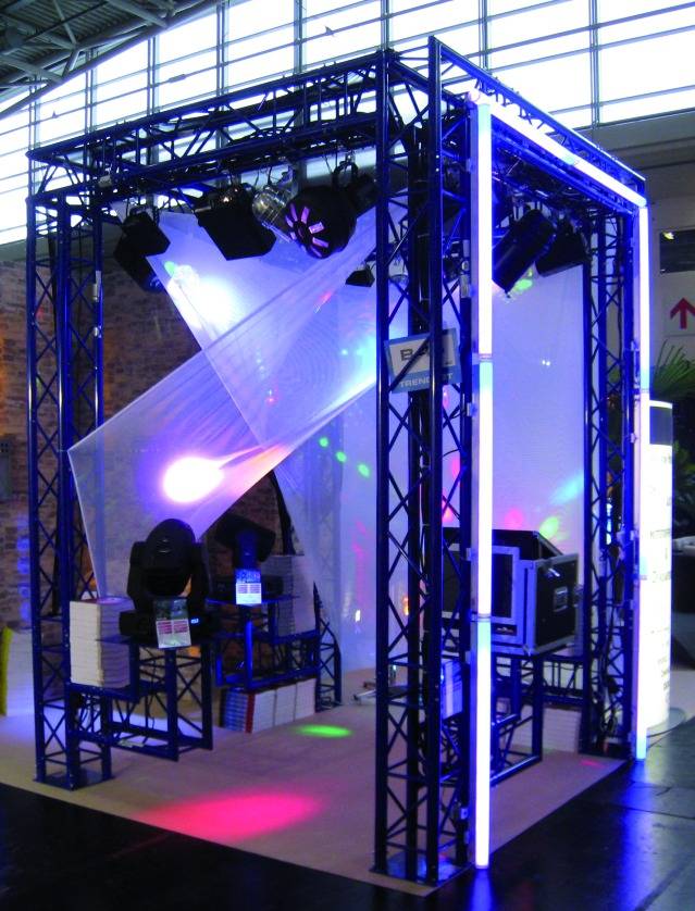 Een tentoonstellingsinstallatie met een blauw metalen frame, lichteffecten en audiovisuele techniek in een beurromgeving.