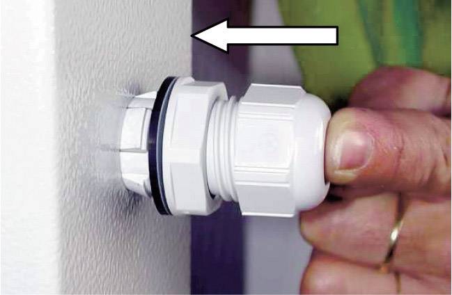 Persoon trekt kunststof schroefverbinding door opening in muur. Pijl geeft de treekrichting aan. Hand benadrukt het belang van de handeling.