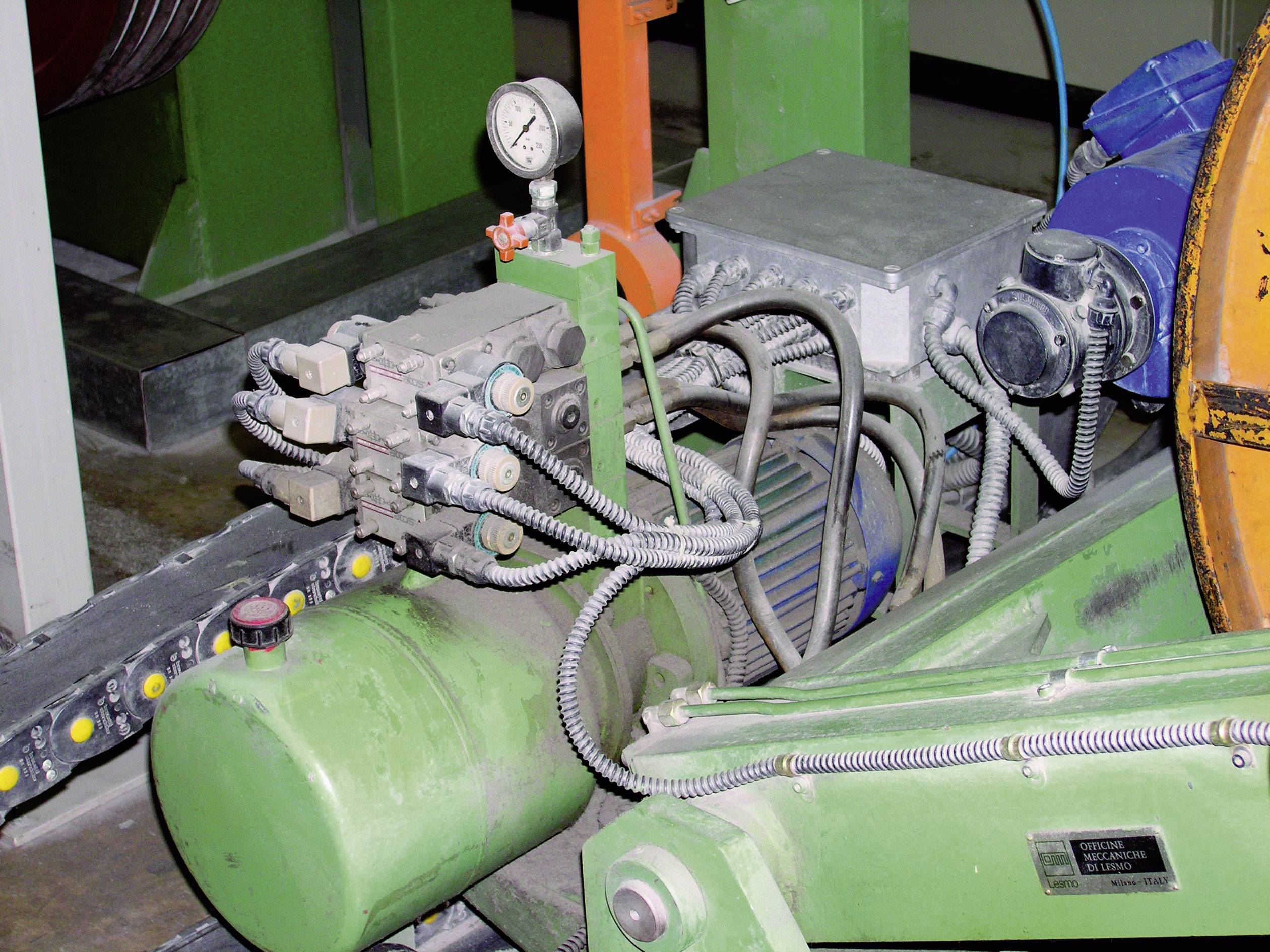 Industriële installatie met groene hydraulische pomp, meerdere slangen en manometer.