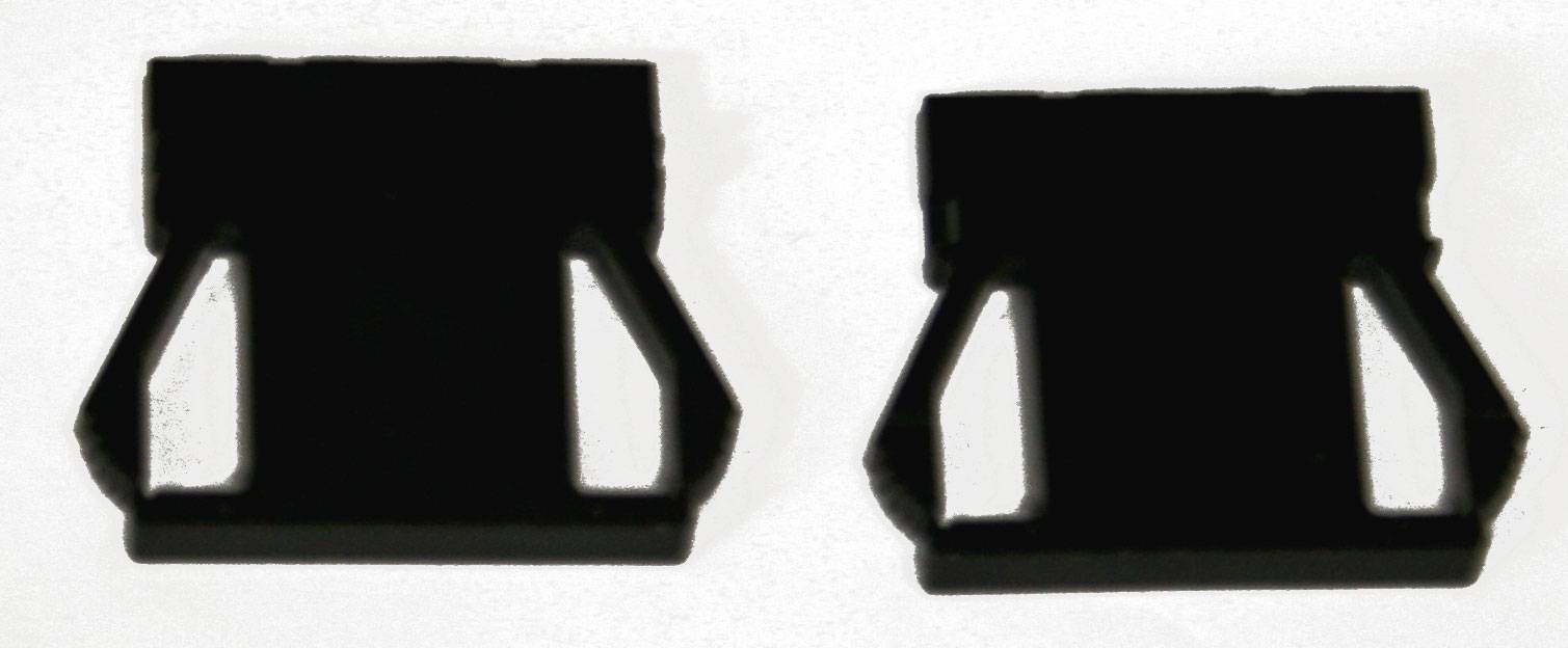 Twee zwarte, rechthoekige kunststof afsluitingen met zijdelingse inkepingen, op een witte achtergrond. Laboratoriumaccessoire of gereedschapsonderdeel.