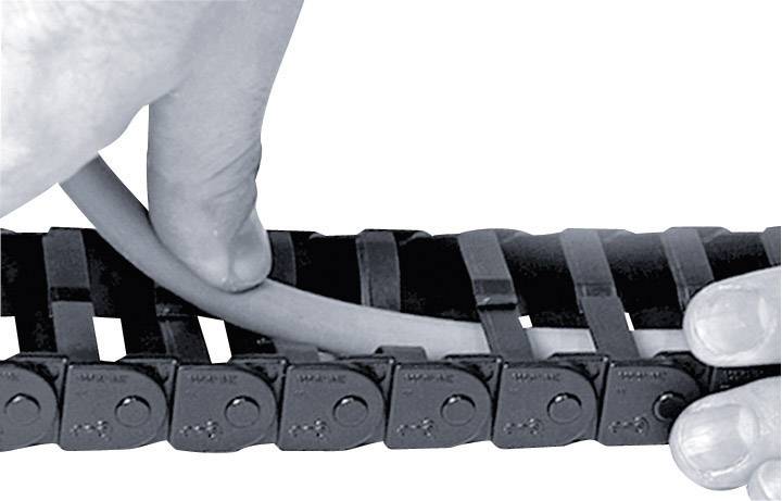 Een hand legt een kabel in een zwarte energiegeleidingsketting. De ketting heeft meerdere schakels die de kabel ordenen en beschermen.