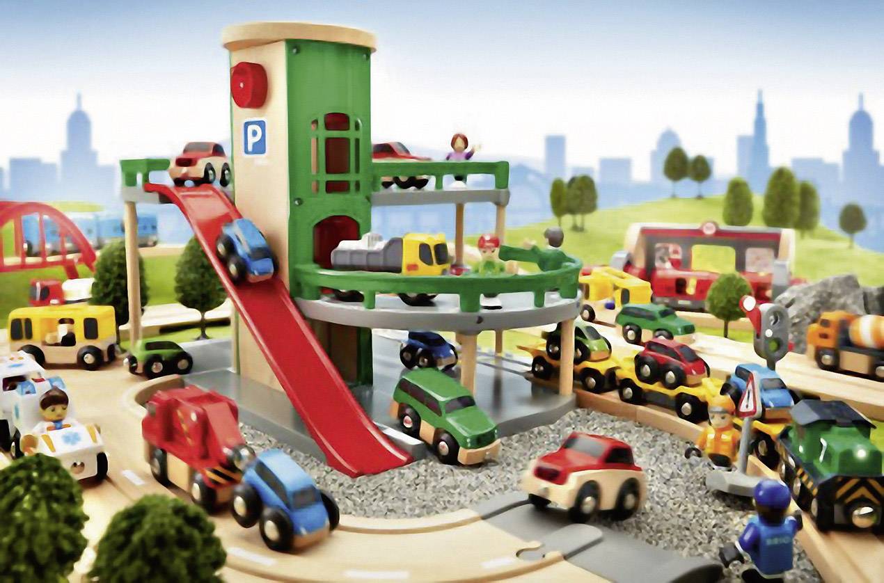 Een kleurrijke speelgoed-parkeerplaats met verschillende voertuigen en figuren. Op de achtergrond zijn bomen en gestileerde gebouwen te zien.