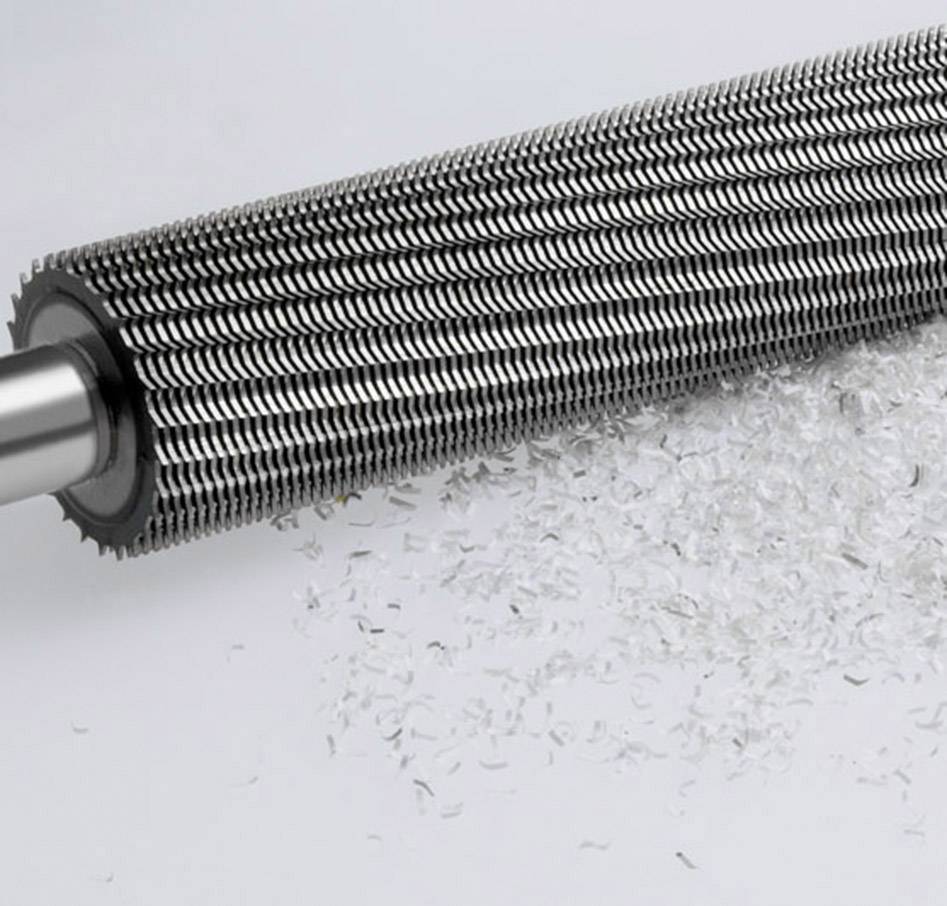 Een grote metalen rol met scherpe messen die witte plastic spaanders versnippert.